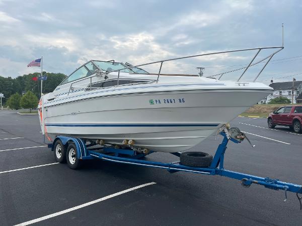 Slide: The Image of 1989 Sea Ray 230 Weekender boat on a blue trailer in a parking lot. - 2