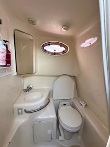 Slide: The Image of 1998 Sea Ray 290 Sundancer bathroom with sink, toilet, and porthole window. - 18
