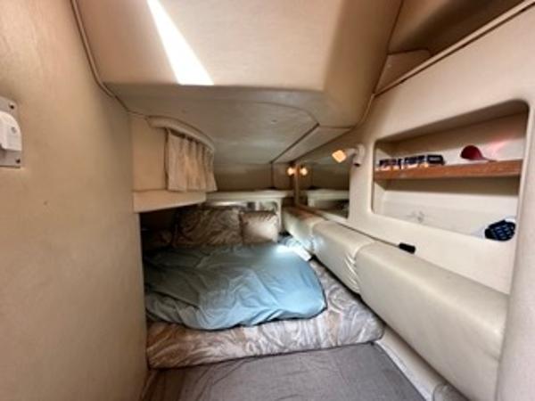 Slide: The Image of 1998 Sea Ray 290 Sundancer cabin interior with bed and storage shelves. - 19