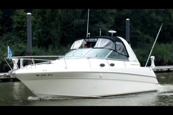Slide: The Image of 1998 Sea Ray 290 Sundancer cruising on a calm river near a dock. - 3