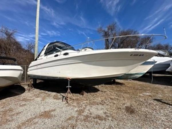 Slide: The Image of 1998 Sea Ray 290 Sundancer boat on dry land under a clear blue sky. - 4