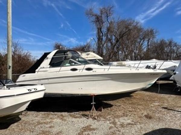 Slide: The Image of 1998 Sea Ray 290 Sundancer boat on dry land with blue sky background. - 5