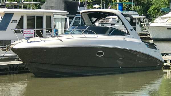 Slide: The Image of 2013 Sea Ray 310 Sundancer docked at marina, sleek design, calm water. - 0