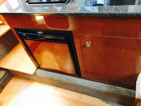 Slide: The Image of 2013 Sea Ray 310 Sundancer interior with wood cabinetry and compact refrigerator. - 32