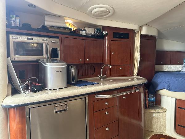 Slide: The Image of 2006 Sea Ray 340 Sundancer interior kitchen with microwave, sink, and wooden cabinets. - 45