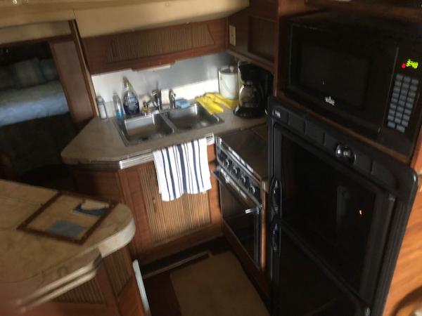 Slide: The Image of 1983 Sea Ray 390 Sport Fisherman kitchen with sink, stove, microwave, and refrigerator. - 23