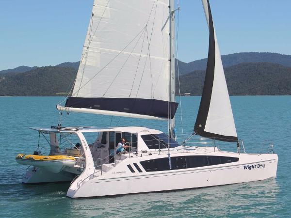 Slide: The Image of 2024 Seawind 1160 Lite catamaran sailing on a serene lake with mountainous backdrop. - 1