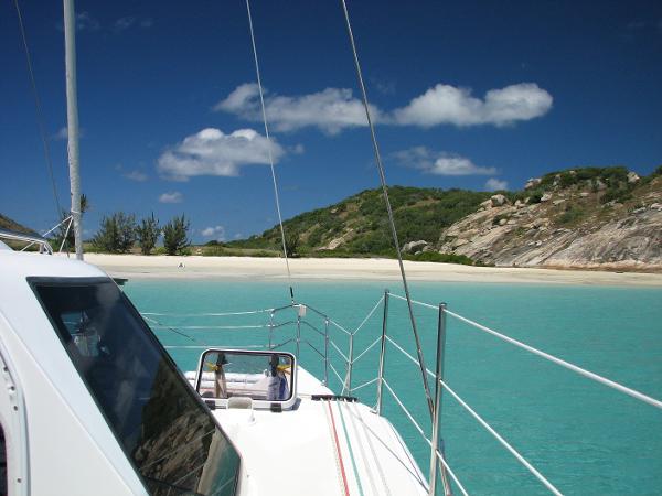 Slide: The Image of Seawind 1160 Lite 2024 catamaran anchored near a tropical beach with clear turquoise water. - 13