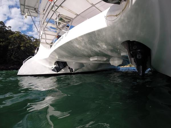 Slide: The Image of 2024 Seawind 1160 Lite catamaran on water, close-up view of hull and outboard motors. - 28