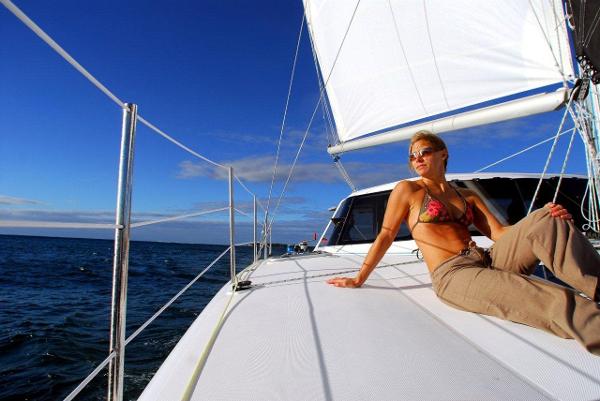Slide: The Image of Woman relaxing on 2024 Seawind 1160 Lite sailboat under clear blue sky. - 4