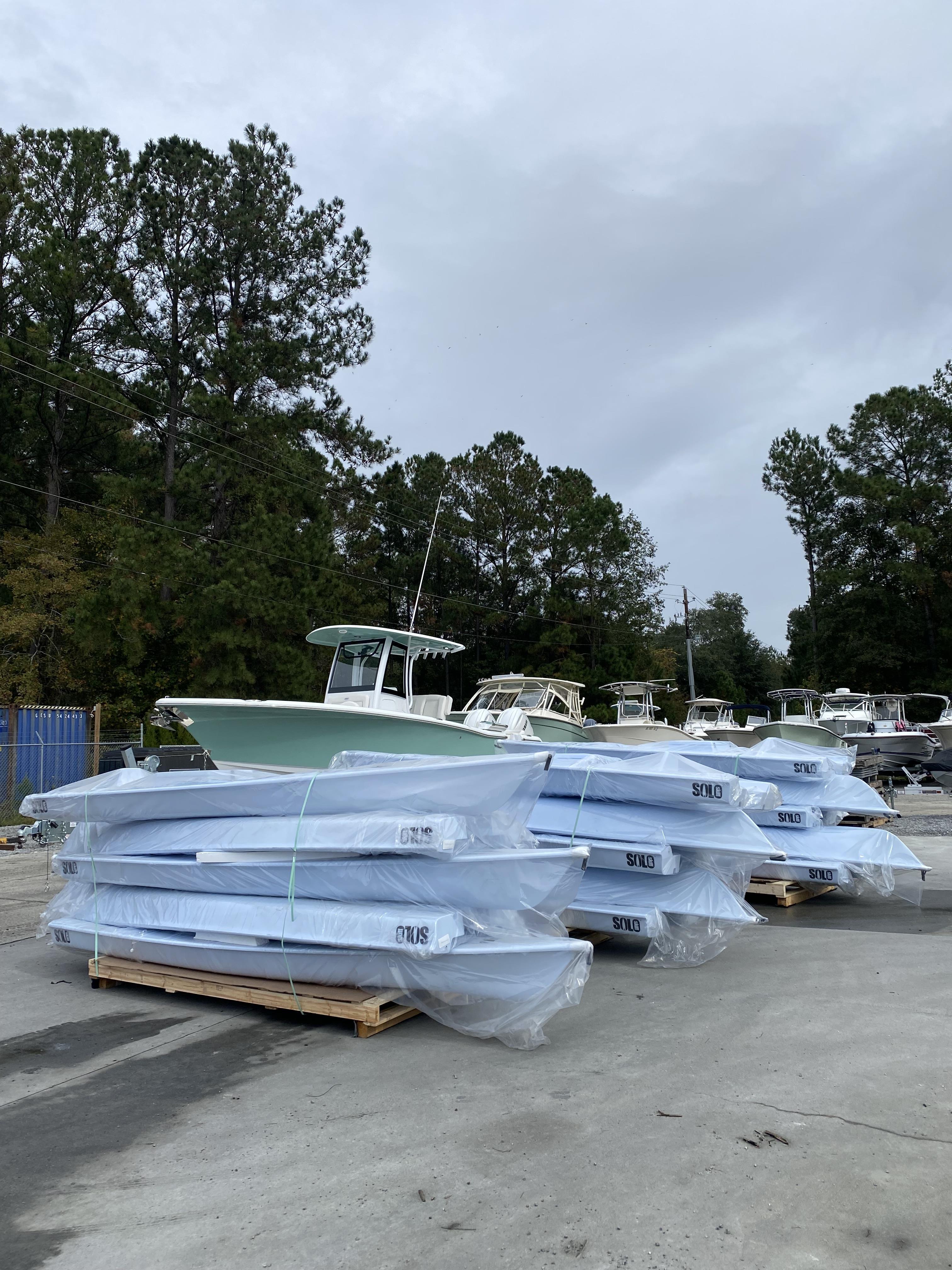 Slide: The Image of Stacked 2023 Solo Skiff boats in a boatyard, wrapped and ready for delivery. - 2