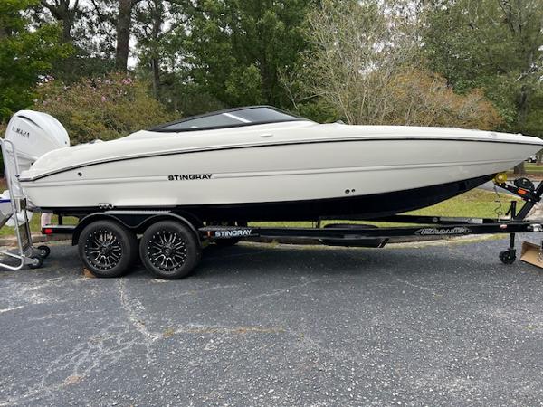 Slide: The Image of 2024 Stingray 230SX boat on trailer, parked outdoors. - 1