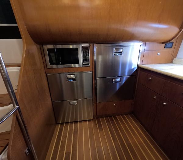 Slide: The Image of Tiara Yachts 2004 5200 Sovran Salon kitchen with stainless steel appliances and wooden cabinetry. - 12