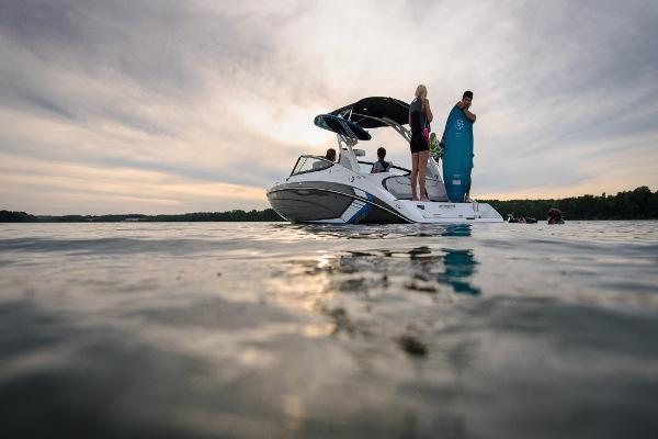 Slide: The Image of 2023 Yamaha Boats 212X on a serene lake at sunset with people onboard. - 1