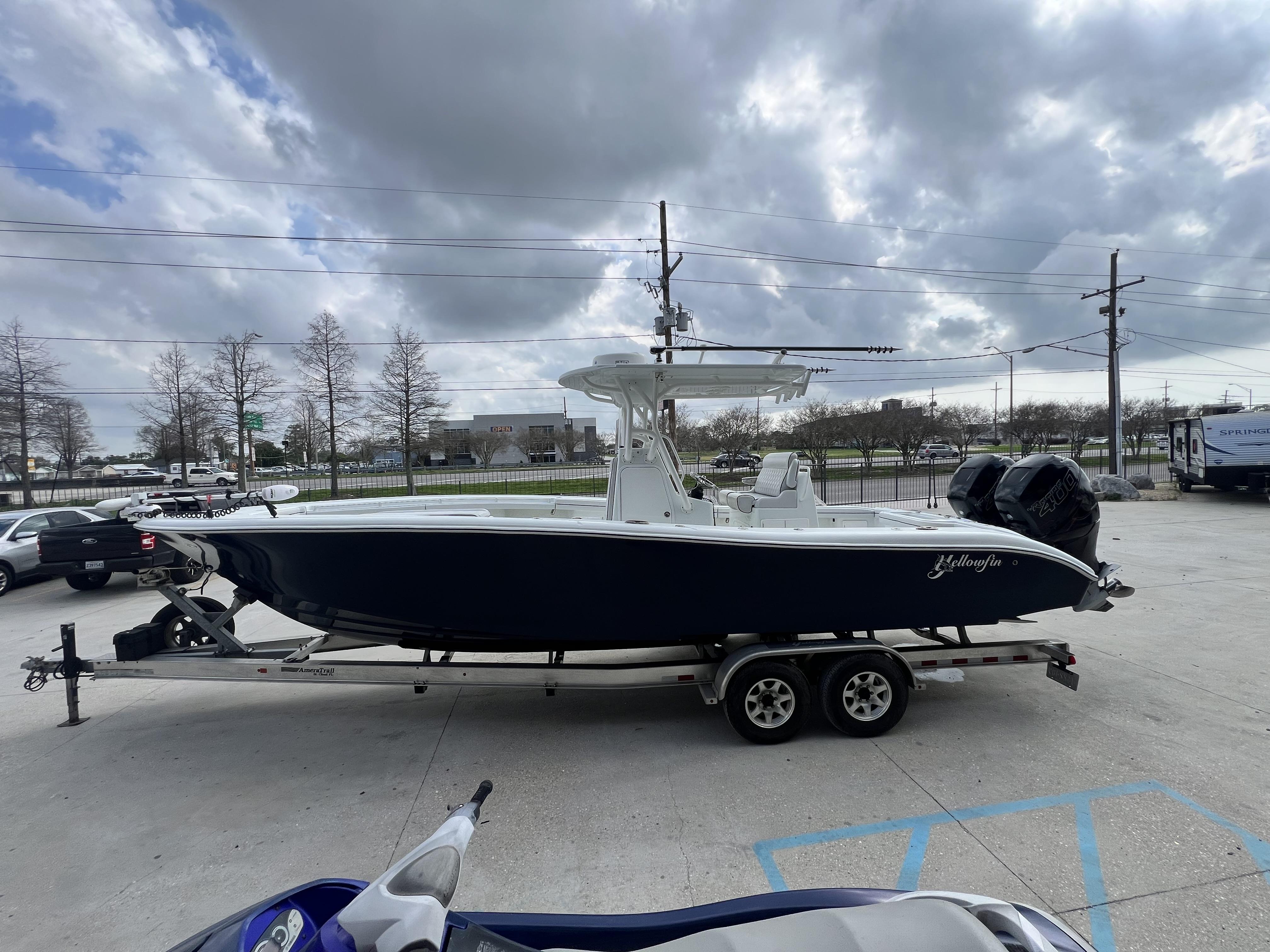 Slide: The Image of 2018 Yellowfin 29 boat on a trailer in a parking lot under cloudy skies. - 2